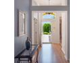 Inviting foyer with light blue walls, wood floors, and an open view to the outdoors through a glass front door at 25243 River Crest Dr, Leesburg, FL 34748