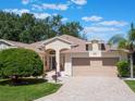 Charming home featuring a brick driveway, well-maintained landscaping, and a welcoming two-car garage at 25243 River Crest Dr, Leesburg, FL 34748