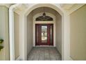 The front entrance features a beautiful glass door framed by an arched entryway, offering a welcoming glimpse inside at 3411 Eisenhower Way, The Villages, FL 32163