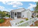 Charming home featuring a screened porch and a well-maintained yard with decorative white picket fence at 412 Hildalgo Dr, The Villages, FL 32159