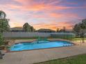 Relaxing pool with built-in seating, set against a colorful sunset sky and white privacy fence at 4730 Se 31St St, Ocala, FL 34480