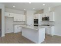 Bright kitchen with white cabinets, an island with a sink, stainless steel appliances and stylish flooring at 5025 Balsam Falls Rd, Deland, FL 32724