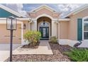 Close up of home's front door, landscape, walkway, and front sidelight window with green shutters at 5944 Hickey Way, The Villages, FL 32163