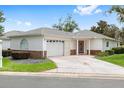 Charming single-story home with a well-manicured lawn, decorative driveway, and inviting front door at 8608 Se 141St Street Rd, Summerfield, FL 34491