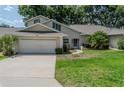 Inviting exterior showcasing a two-car garage, lush green lawn, and well-maintained landscaping at 8705 Village Green Blvd, Clermont, FL 34711