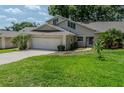 Beautiful house featuring a well-kept lawn, a two-car garage, and a charming walkway to the front door at 8705 Village Green Blvd, Clermont, FL 34711