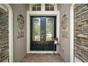 Elegant double front doors with glass panels, flanked by decorative wall accents and stone details at 926 Wood Briar Loop, Sanford, FL 32771