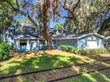 Charming blue home with lush lawn, mature trees with Spanish Moss, and train tracks in the yard at 1107 Northshore Dr, Eustis, FL 32726