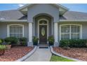 Up close exterior shot of an inviting doorway framed by pillars and manicured shrubbery, creating a welcoming entrance at 11437 Alameda Sandra Dr, Clermont, FL 34711