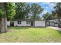 Inviting single-story home featuring a well-maintained lawn, a covered parking area, and mature trees offering plenty of shade at 121 Mason Park Dr, Daytona Beach, FL 32117