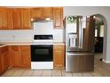 Functional kitchen with tile flooring, wood cabinets, stainless steel refrigerator, and modern black range at 23515 Poinsettia Ave, Fruitland Park, FL 34731