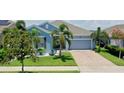 Charming single-story home featuring a well-maintained lawn, lush landscaping, and a two-car garage at 245 Blue Cypress Dr, Groveland, FL 34736