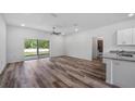 Open-concept living room with wood-look floors and a sliding glass door to the yard at 24912 Jefferson St, Astatula, FL 34705