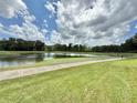 Scenic golf course view with a tranquil pond, lush greenery, and clear blue skies with fluffy white clouds at 26612 Bella Vista Dr, Howey In The Hills, FL 34737