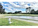Scenic golf course view with a pond, trees and blue sky with clouds in the background at 26612 Bella Vista Dr, Howey In The Hills, FL 34737