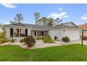 Inviting single-story home with a well-maintained lawn, a two-car garage, and colorful plants at 2712 Plainridge Loop, The Villages, FL 32162