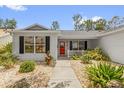 Charming home with a bright red front door and attractive landscaping at 2712 Plainridge Loop, The Villages, FL 32162