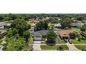 An aerial view of a single-story home with a lush green lawn and a backdrop of mature trees and neighborhood homes at 3677 Park Green Ct, Tavares, FL 32778