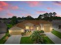 Beautifully landscaped, this tan home features an eye-catching red front door and a convenient three-car garage at 4716 Heritage Trl, Leesburg, FL 34748