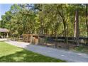Fenced chicken coop, adjacent to a long driveway, nestled among mature trees, offering a rural lifestyle at 5581 Sw 197Th Ter, Dunnellon, FL 34431