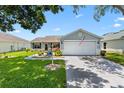 Inviting home with a well-kept lawn, concrete driveway, and attached two-car garage at 612 Lisbon Ln, The Villages, FL 32159