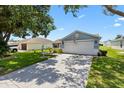 Pleasant single-Gathering home featuring a long concrete driveway and a two-car garage at 612 Lisbon Ln, The Villages, FL 32159