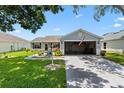 Bright home with a well-kept lawn, concrete driveway, and open two-car garage at 612 Lisbon Ln, The Villages, FL 32159