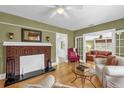 Cozy living room featuring a brick fireplace, wood floors, and ample natural light at 647 E 3Rd Ave, Mount Dora, FL 32757