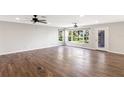 Spacious living room with wood-look tile flooring, ceiling fans, and natural light from large windows at 7378 Ne 49Th Ln, Wildwood, FL 34785