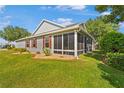 Exterior view of a gray home featuring a screened porch, manicured lawn and attractive landscaping at 8980 Se 176Th Limerick Ln, The Villages, FL 32162