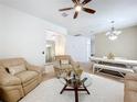Comfortable living space with plush seating, ceiling fan, glass coffee table, and view into dining area at 1454 Westbury Dr, Clermont, FL 34711
