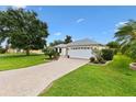 Well-maintained single-story home featuring a paver driveway, lush lawn, and mature landscaping at 1514 Vandam St, The Villages, FL 32162
