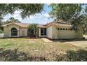 Charming single-story home with a well-manicured lawn, mature trees, and attached two-car garage at 15837 Hidden Lake Cir, Clermont, FL 34711