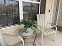 Cozy front porch sitting area with glass table, chairs, and view of lush greenery at 1723 Banberry Run, The Villages, FL 32162