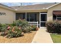 Welcoming screened front porch surrounded by mature landscaping and colorful rose bushes at 1723 Banberry Run, The Villages, FL 32162