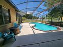 A screened-in pool and patio with seating overlooks a white fence and green pasture at 21206 Canoe Pass St, Clermont, FL 34715