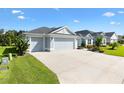 Street view of a single Gathering home with a three car garage, concrete driveway and mature landscaping at 2321 Demarco Dr, The Villages, FL 32163