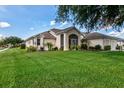 Well-maintained home featuring a manicured lawn and decorative landscaping at 27146 Greenfly Orchid Ln, Leesburg, FL 34748