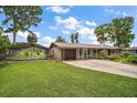 Charming single-story home with a well-manicured lawn, carport, and attached garage at 31941 Tropical Shores Dr, Tavares, FL 32778