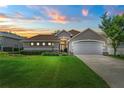 Home at sunset featuring a green lawn, manicured hedges, and a two-car garage at 3257 Baltic Sea Blvd, Tavares, FL 32778