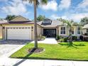 Charming home featuring a two-car garage, manicured lawn, and mature palm trees at 3519 Arlington Ridge Blvd, Leesburg, FL 34748