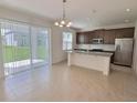 Open-concept kitchen featuring an island, stainless steel appliances, and sliding doors to the patio at 358 Switchgrass Loop, Minneola, FL 34715