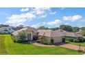 Spacious single-story home with brick driveway, two-car garage, and beautiful landscaping under a blue sky at 39504 Hillrise Ln, Lady Lake, FL 32159