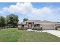 Charming front exterior with well-manicured lawn and garden, attached garage, and fenced yard at 40143 Babb Rd, Umatilla, FL 32784