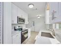 Modern kitchen boasts white cabinets, stainless steel appliances, and ample counter space at 841 S Michigan Ave, Groveland, FL 34736