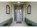 Covered front entry featuring an ornate front door, wall sconces and a colorful entrance mat at 946 Isle Of Palms Path, The Villages, FL 32162