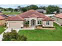Inviting single-story home featuring a red tile roof, arched windows, and a lush green lawn at 10240 Kabana Blvd, Clermont, FL 34711