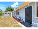 Inviting entrance of a home with secure black door and matching detached garage at 1119 Pine Ave, Tavares, FL 32778