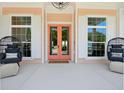 Inviting front porch with double glass doors, comfortable seating and decorative lighting at 1127 Fiesta Key Cir, Lady Lake, FL 32159