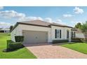 Attractive home exterior with a brick driveway, two-car garage, and manicured landscaping at 11313 Little Nellie Dr, Clermont, FL 34711